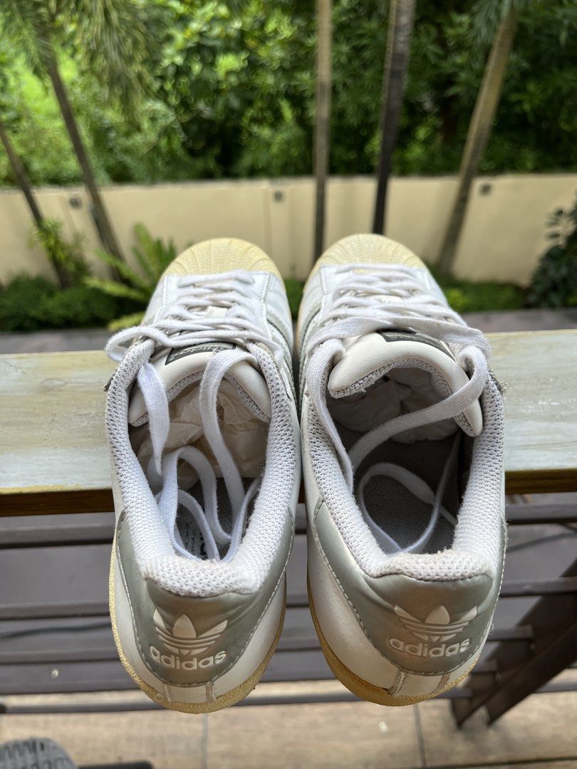 Adidas Superstar Shoes Bundle (Category: Sneakers) located in Manila. Submitted by tanfinds (Listing ID 1464987441, Image 2). Description: - Bundle includes: 2 pairs of authentic Adidas Superstar sneakers - Pair 1: Classic white leather with silver stripes and shell toe - Pair 2: Black slip-on style with crisscross elastic bands - Features: Iconic rubber shell toes and durable textured outsoles - Condition: Soles show normal yellowing from age an