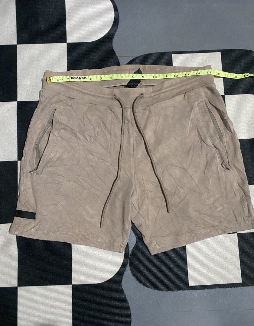 Alphalete Tan Drawstring Athletic Shorts (Category: Shorts) located in Las Pinas. Submitted by matilliano76499 (Listing ID 1465085508, Image 1). Description: - Brand: Alphalete - Color: Tan - Material: 95% Cotton, 5% Elastane - Waist: ~15" flat across (adjustable elastic drawstring) - Length: ~18.5" - Pockets: Two secure zippered side pockets + rear patch pockets - Details: Black rubber brand patches on lower leg and back pocket - Condition: Exce