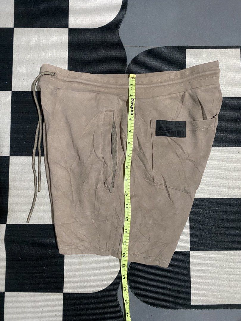 Alphalete Tan Drawstring Athletic Shorts (Category: Shorts) located in Las Pinas. Submitted by matilliano76499 (Listing ID 1465085508, Image 2). Description: - Brand: Alphalete - Color: Tan - Material: 95% Cotton, 5% Elastane - Waist: ~15" flat across (adjustable elastic drawstring) - Length: ~18.5" - Pockets: Two secure zippered side pockets + rear patch pockets - Details: Black rubber brand patches on lower leg and back pocket - Condition: Exce