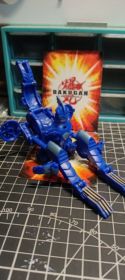Aquos Akwimos + Gigarth (drop open) (Category: Action & Battle Toys) located in Binan City. Submitted by sir_macs (Listing ID 1465099971, Image 1). Description: -DROP OPEN, NEEDS ASSISTANCE IN OPENING. - Blue Bakugan action figure in fully transformed robot mode - Includes matching trading card - Articulated arms and legs for posing - Bright blue plastic with clean surfaces and green painted eye details - Perfect for display or tabletop play.