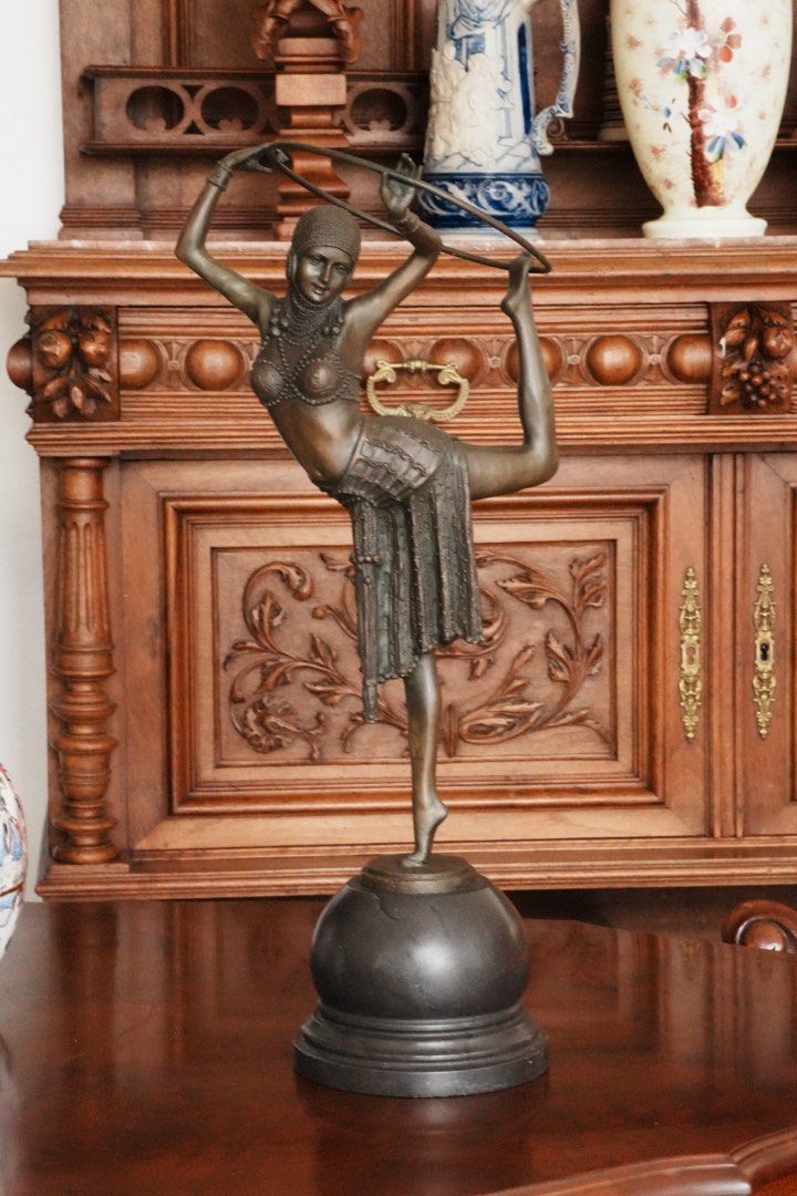 Art Deco-Style Hoop Dancer - After Demétre Chiparus (Category: Vintage Collectibles) located in Manila. Submitted by heleensym (Listing ID 1464969706, Image 3). Description: An elegant dancer balances on one foot, holding a hoop overhead in a graceful theatrical pose. Her richly detailed costume and beaded headdress evoke the glamour of Art Deco decorative sculpture. The figure has a warm brown-toned finish and stands on a dark, domed stone base.