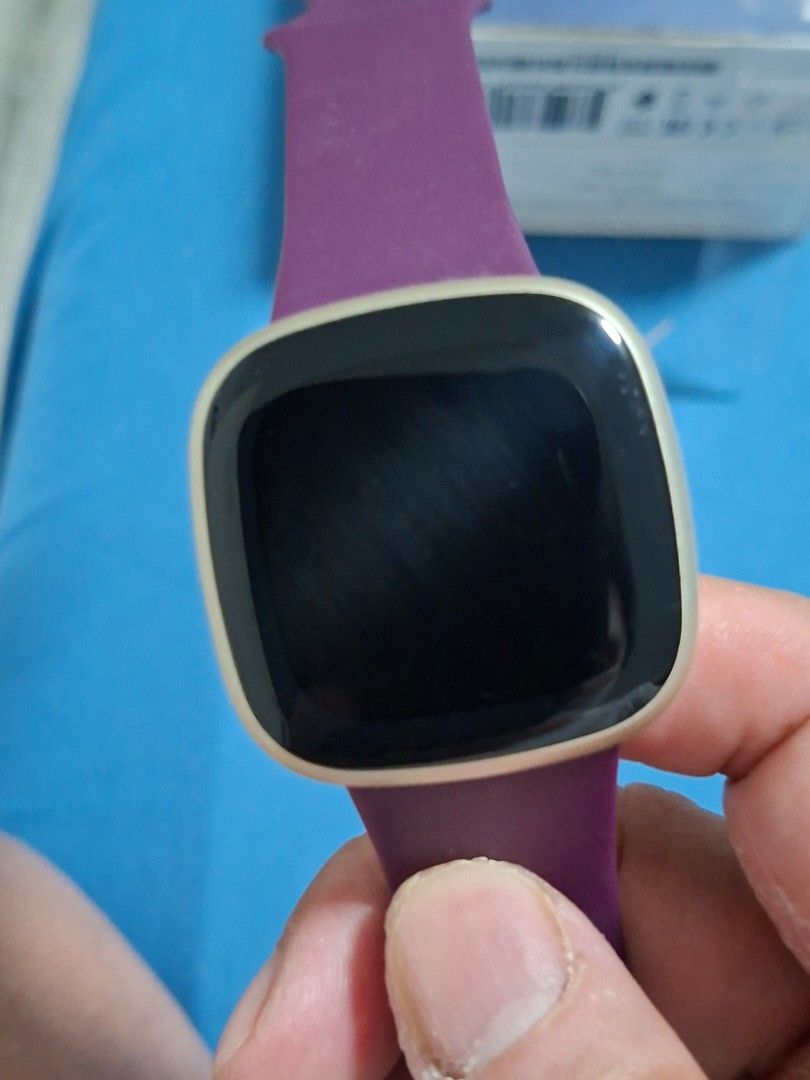 Authentic Fitbit Versa 3 (Category: Wearables & Smart Watches) located in Paranaque City. Submitted by tabsi76 (Listing ID 1465093192, Image 2). Description: - Brand: Fitbit (Authentic) - Model: Versa 3 - Color: Gold case with Purple strap - Inclusions: Original box and charging cable - Condition: Pre-owned, shows minor wear/scratches on the side casing, fully functional - Features: Built-in GPS, heart rate monitor, fitness and health tracking - 