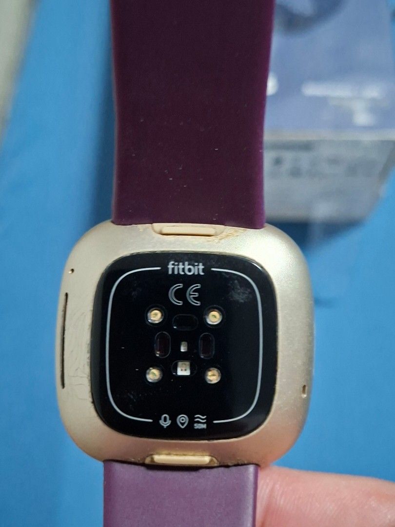 Authentic Fitbit Versa 3 (Category: Wearables & Smart Watches) located in Paranaque City. Submitted by tabsi76 (Listing ID 1465093192, Image 3). Description: - Brand: Fitbit (Authentic) - Model: Versa 3 - Color: Gold case with Purple strap - Inclusions: Original box and charging cable - Condition: Pre-owned, shows minor wear/scratches on the side casing, fully functional - Features: Built-in GPS, heart rate monitor, fitness and health tracking - 