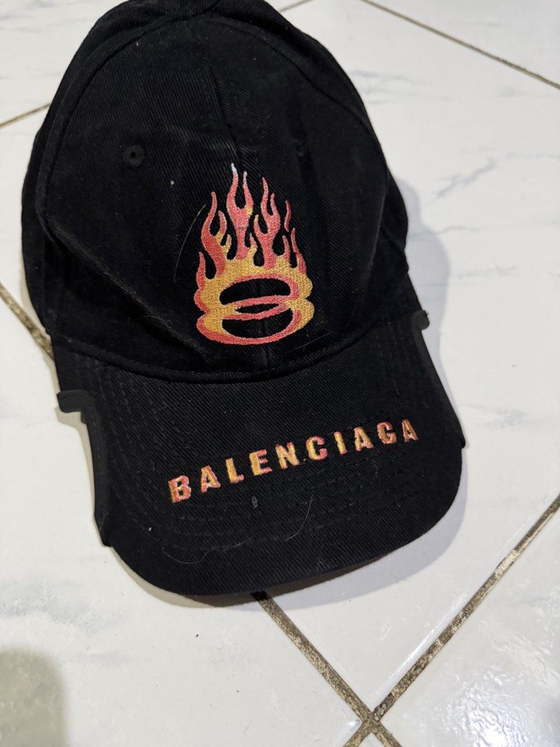 Balenciaga Flame Embroidery Baseball Cap Black (Category: Caps & Hats) located in Manila. Submitted by swag_shop00 (Listing ID 1465102530, Image 2). Description: - Brand: Balenciaga - Color: Black - Material: 100% Cotton (Made in Italy) - Design: Flame embroidery on front and back panels - Details: Balenciaga logo embroidered on the curved brim - Fit: Adjustable strap at the back - Condition: Clean interior lining with proper brand tags attached.