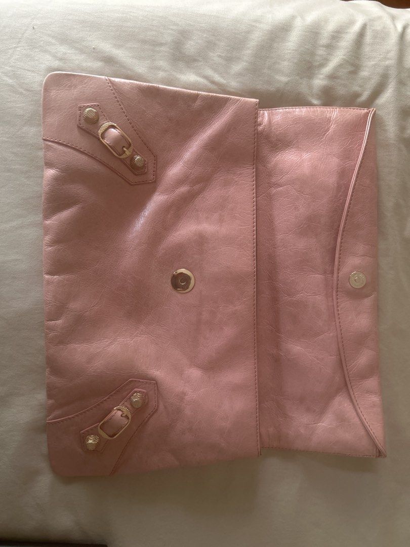Balenciaga Pink Leather Envelope Clutch (Category: Luxury Bags & Wallets) located in Manila. Submitted by eeerk (Listing ID 1464970406, Image 2). Description: - Brand: Balenciaga - Style: Envelope clutch in soft pink leather - Hardware: Gold-toned with signature stud and buckle details - Closure: Fold-over flap with magnetic snap - Pockets: Convenient front zip pocket - Interior: Dark lining with Balenciaga Paris leather brand patch - Capacity: S