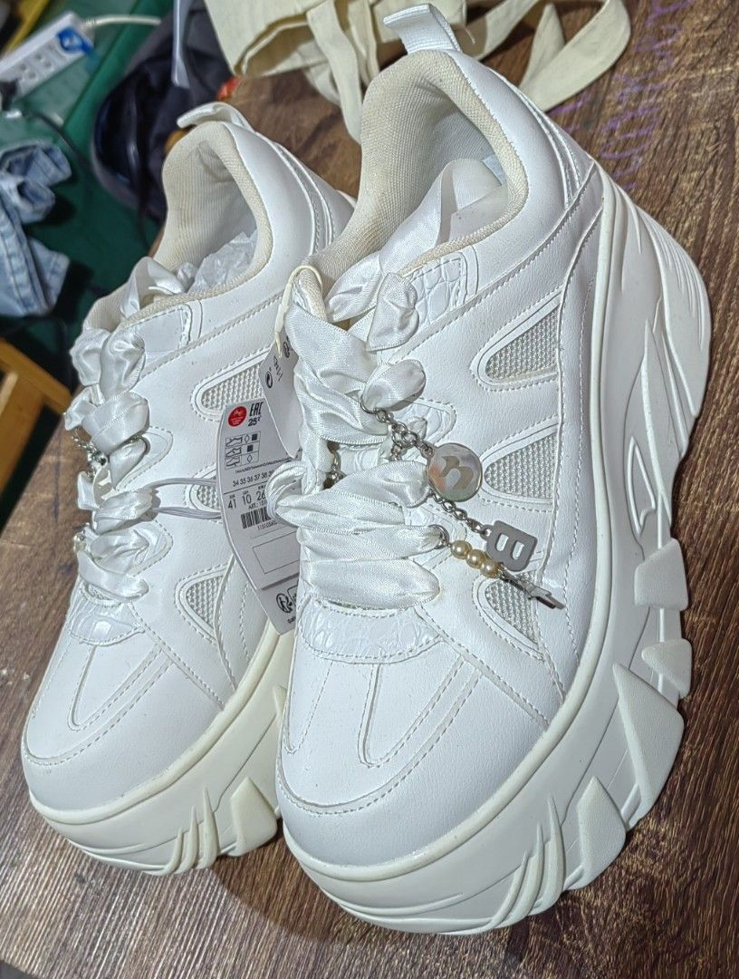 Bershka Chunky White Platform Sneakers Size 41 (Category: Sneakers) located in Muntinlupa City. Submitted by jaz_things (Listing ID 1465169846, Image 2). Description: - Brand new with original store tags - Trendy all-white colorway with a thick platform sole and chunky tread pattern - Features unique wide ribbon laces - Comes with an attached charm chain detail featuring pearls and a letter pending - unused .