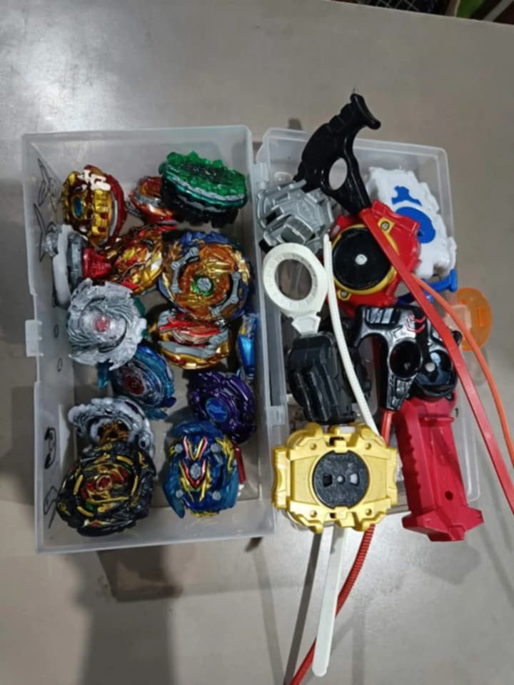 Beyblade Lot (Category: Action & Battle Toys) located in Manila. Submitted by grlfncs.mon31 (Listing ID 1465085538, Image 1). Description: - Complete Beyblade Burst battle set - Includes multiple tops with golden, blue, black, and white layers - Comes with various launcher grips and winders - Includes a clear storage case for easy organization - Great as a starter set or to expand your current collection - Condition: Good / Ready to play - Meet-u