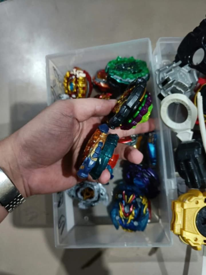Beyblade Lot (Category: Action & Battle Toys) located in Manila. Submitted by grlfncs.mon31 (Listing ID 1465085538, Image 3). Description: - Complete Beyblade Burst battle set - Includes multiple tops with golden, blue, black, and white layers - Comes with various launcher grips and winders - Includes a clear storage case for easy organization - Great as a starter set or to expand your current collection - Condition: Good / Ready to play - Meet-u