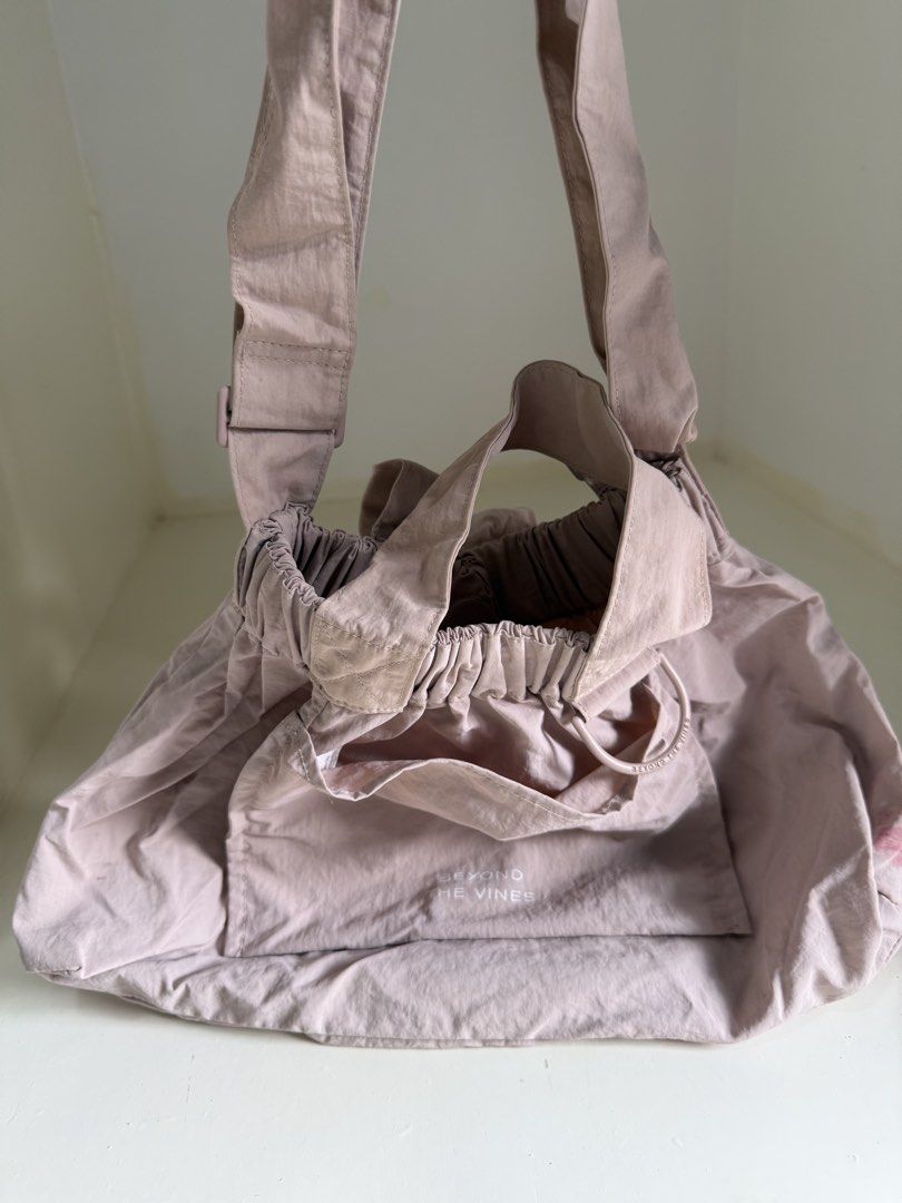 Beyond The Vines Dumpling Bag (Category: Shoulder Bags) located in Quezon City. Submitted by reivia.vend (Listing ID 1465011247, Image 1). Description: - Brand: Beyond The Vines - Color: Dusty Pink - Material: Lightweight nylon - Closure: Drawstring with toggle at the top - Features: Front pocket with brand logo, adjustable strap with hardware - Packable: Folds neatly into its own attached pouch - Flaw Note: There is a small red stain on one side