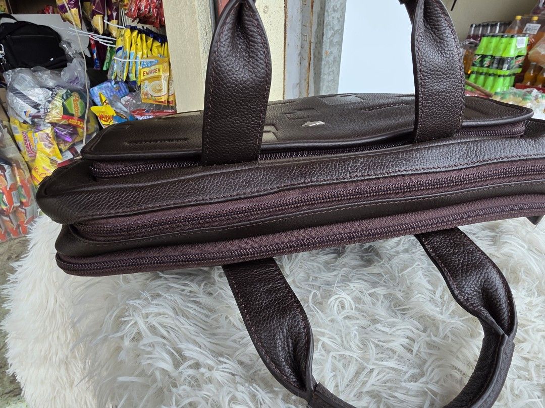 Braun Buffel Dark Brown Leather Laptop Briefcase (Category: Briefcases) located in Lemery. Submitted by venus23 (Listing ID 1465094160, Image 3). Description: - Brand: Braun Buffel - Material: Genuine leather in dark brown with embossed square geometric pattern - Hardware: Silver-tone with iconic metal bull logo emblem - Interior: Monogram fabric lining with multiple zippered compartments, pen loops, and structured organizers - Handles: Sturdy du