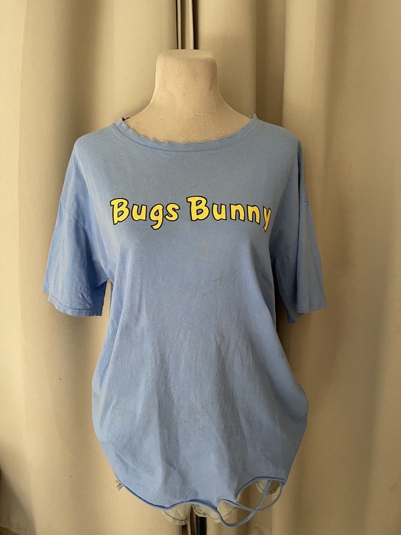 Bugs Football Luck Blue Tee (Category: Shirts) located in Cainta. Submitted by zlove111 (Listing ID 1464970052, Image 2). Description: - Color: Light blue - Design: Bugs Bunny front branding with a large football graphic and 'FOOTBALL LUCK' text on the back - Fit: Relaxed fit with short sleeves - Details: Trendy slightly tattered - Style: Casual everyday top, great for streetwear with minimal washable yellowstain from bale see pic .