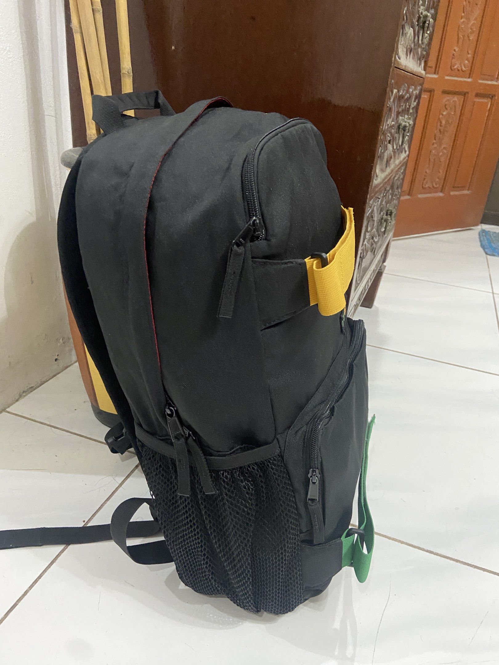 Burton Black Rasta Backpack with Yellow and Green Straps (Category: Backpacks) located in Pilar. Submitted by romeoabejo54125 (Listing ID 1464984342, Image 2). Description: - Brand: Burton - Color: Black with yellow and green strap accents - Design: Multi-color embroidered Burton text on front - Storage: Mesh side pockets on both sides - Comfort: Quilted back panel with red stitching and padded shoulder straps - Condition: Clean fabric inside and