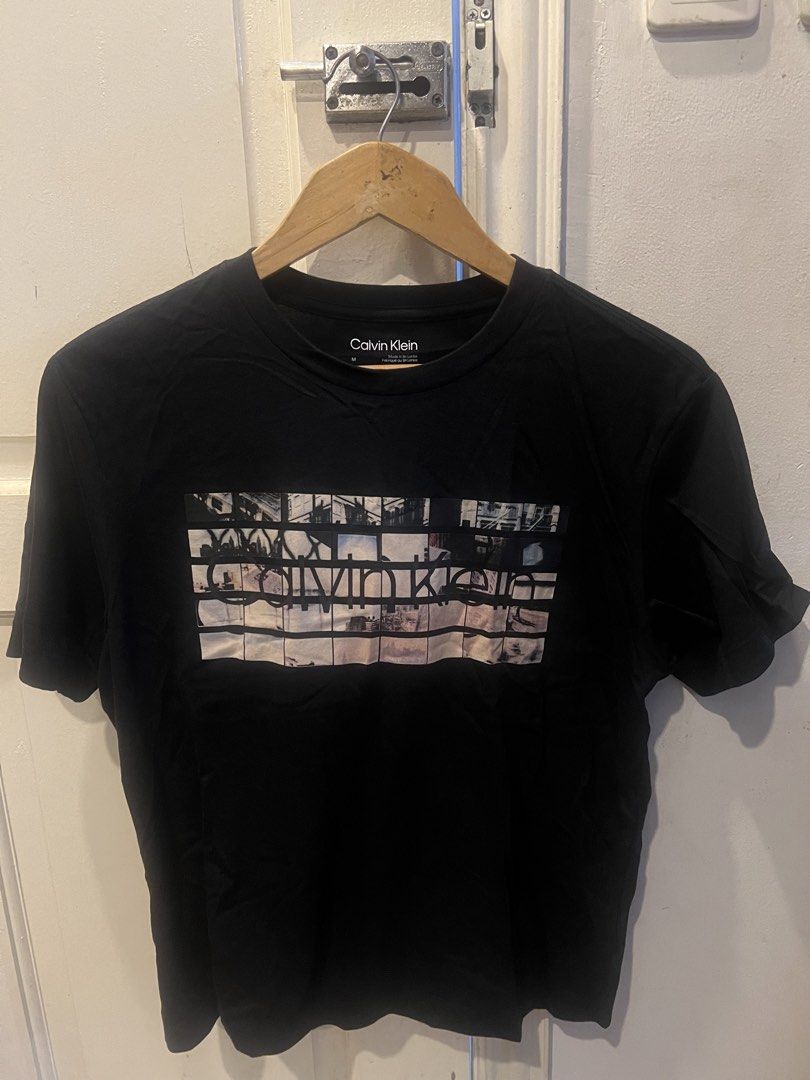 Calvin Klein Graphic Tee Black Size M (Category: Tshirts & Polo Shirts ) located in Manila. Submitted by cleverstone_21f597 (Listing ID 1464974934, Image 2). Description: - Brand: Calvin Klein - Color: Black - Size: Medium - Design: Chest photo collage graphic with layered brand logo - Neckline: Classic crew neck - Material: Soft, comfortable cotton - Condition: Clean and well-maintained.