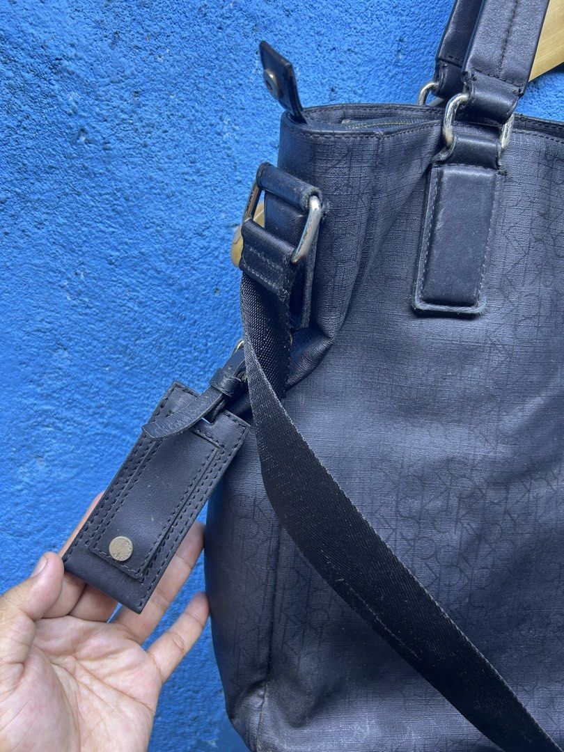 Calvin Klein Monogram Tote Bag with Shoulder Strap (Category: Tote Bags) located in Quezon City. Submitted by thriftxgoods (Listing ID 1465078455, Image 2). Description: Calvin Klein tote bag in dark blue canvas with all-over monogram pattern. Includes dual top handles plus a detachable adjustable crossbody strap. Zipper top closure keeps your items secure. Inside lining shows discoloration near the opening rim, plus an inner zippered pocket with