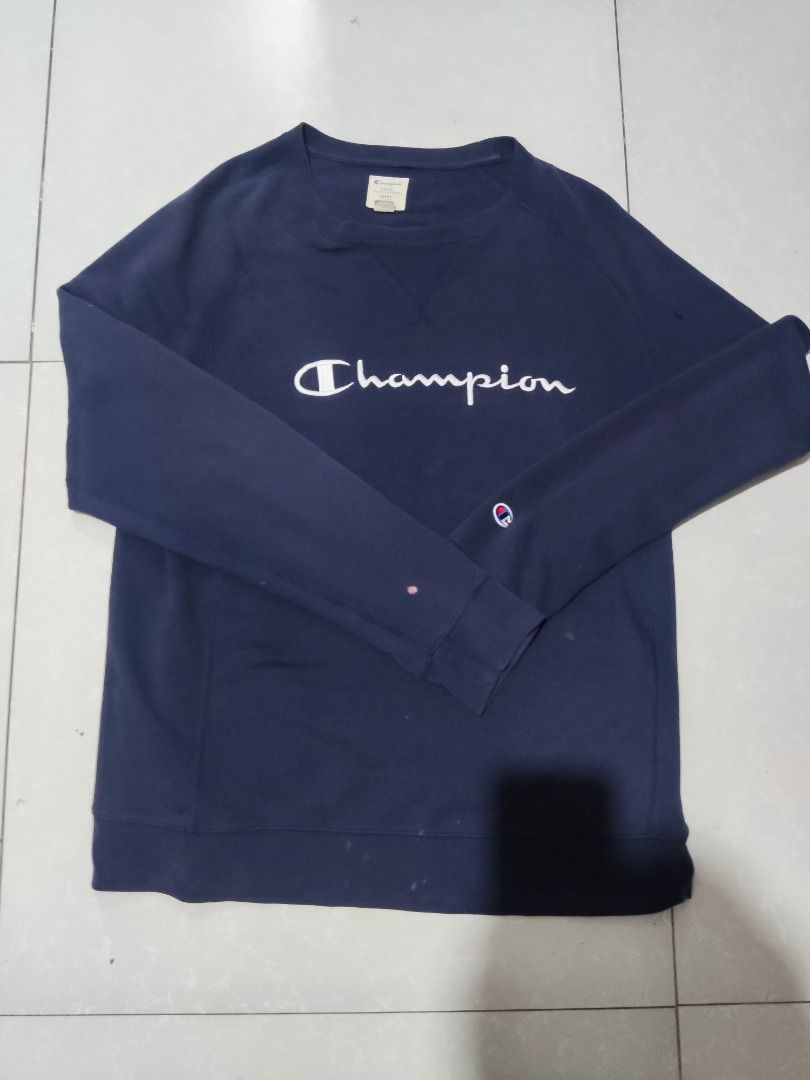 Champion Navy Blue Script Logo Sweatshirt (Category: Coats, Jackets and Outerwear) located in Rizal. Submitted by skilidilidu (Listing ID 1465082903, Image 1). Description: - Color: Navy blue - Brand: Champion - Design: White script logo on chest with small sleeve patch - Style: Classic crewneck pullover with ribbed cuffs and hem - Comfort: Warm and cozy fabric - Condition: Pre-loved, well-maintained dimensions 24.5x 29 issues hole and uneven sli
