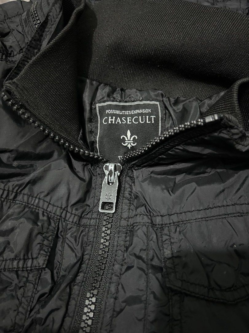 Chasecult Black Utility Jacket Windbreaker with Pockets (Category: Coats, Jackets and Outerwear) located in Manila. Submitted by elnemeeh_05 (Listing ID 1465019564, Image 1). Description: - Brand/Model: Chasecult Black Jacket - Material: Dark textured nylon, lightweight for daily wear - Closure: Full zip front with ribbed collar - Pockets: Multiple functional front pockets with secure button flaps and zipper details - Color: Solid black colorway.