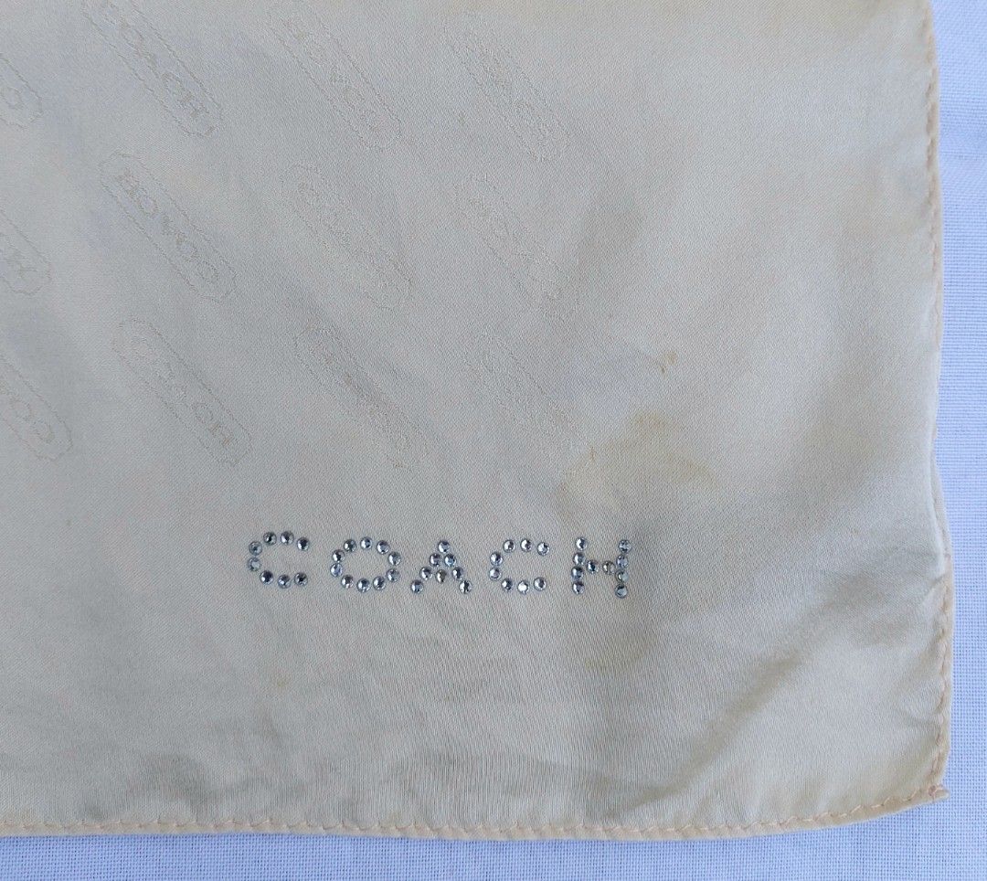 Coach Beige Monogram Silk Scarf with Rhinestone Logo (Category: Scarves) located in Lapu Lapu. Submitted by agnesapm_29813 (Listing ID 1465106411, Image 1). Description: - Brand: Coach - Material: Soft, lightweight silk - Color/Pattern: Pale beige with subtle repeating monogram - Detail: Sparkling crystal rhinestone 'Coach' logo at one corner - Flaw: Small stain, please see last photo - Measurements: 22 x 22 inches .