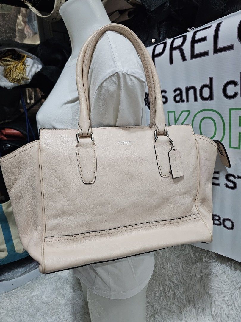 Coach Leather Tote Handbag Peach Pink (Category: Luxury Bags & Wallets) located in Cavite. Submitted by liveriver_514fd1 (Listing ID 1464986359, Image 1). Description: - Brand: Coach - Color: Peach Pink - Material: Genuine Leather - Hardware: Silver-tone - Features: Dual top handles, hanging leather charm tag, and front vertical zipper pocket - Interior: Spacious main compartment for daily essentials - Design: Clean silhouette with subtle front b