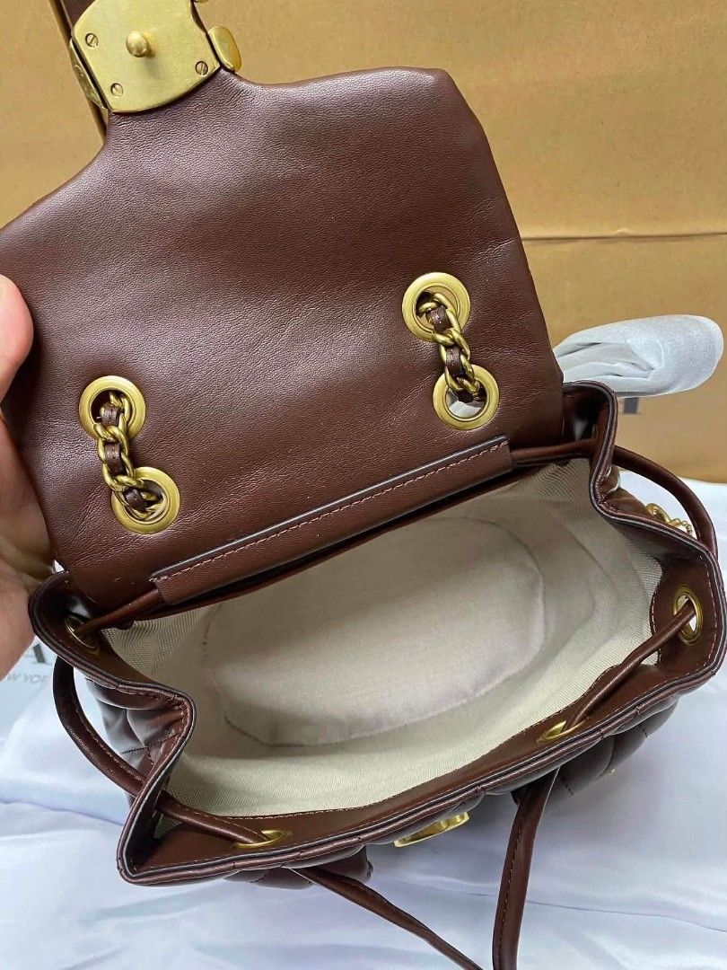 Coach Quilted Leather Backpack (Category: Backpacks) located in Manila. Submitted by onlineshopmate (Listing ID 1465136443, Image 3). Description: - Brand: Coach - Material: Quilted leather in a rich brown shade - Hardware: Antique brass tone - Closure: Signature C turnlock on main flap with drawstring underneath - Pockets: Twin front utility pockets - Straps: Chain top handle and adjustable leather shoulder straps - Condition: Brand new (protect