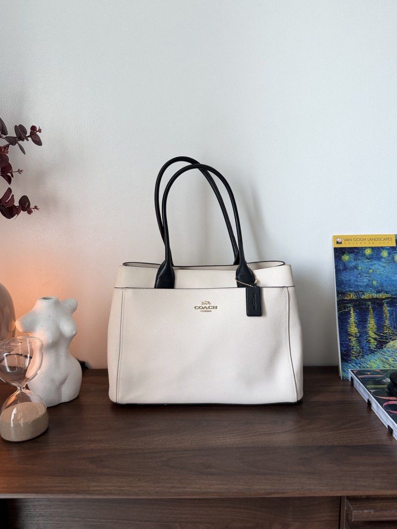 Coach White and Black Leather Tote Bag (Category: Tote Bags) located in Taguig. Submitted by kngrylie (Listing ID 1465055672, Image 1). Description: - Brand: Coach - Condition: like new - Material: Premium white pebble leather with contrasting black handles - Hardware: Elegant gold-tone hardware with front metal lettering logo - Accessories: Includes matching black leather hangtag - Interior: Divided layout with a secure central zip compartment a