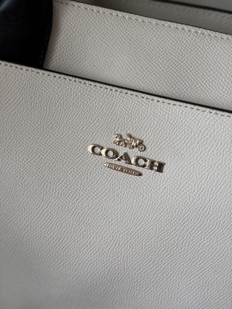 Coach White and Black Leather Tote Bag (Category: Tote Bags) located in Taguig. Submitted by kngrylie (Listing ID 1465055672, Image 3). Description: - Brand: Coach - Condition: like new - Material: Premium white pebble leather with contrasting black handles - Hardware: Elegant gold-tone hardware with front metal lettering logo - Accessories: Includes matching black leather hangtag - Interior: Divided layout with a secure central zip compartment a