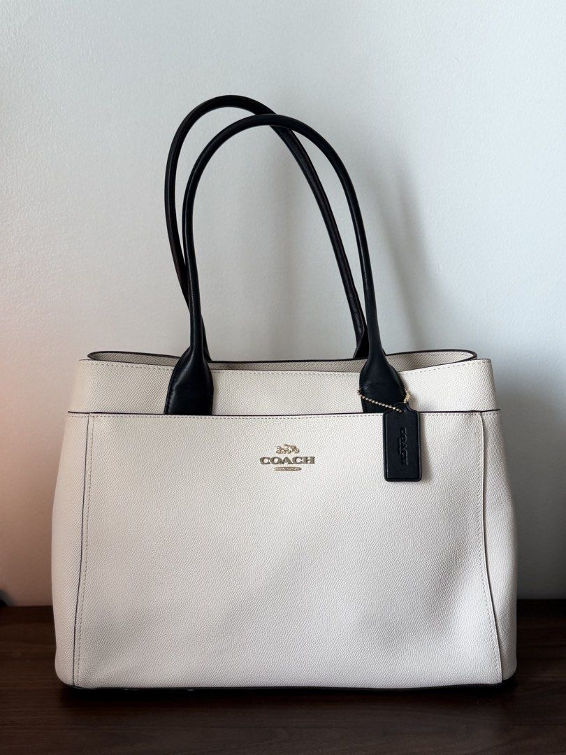 Coach White and Black Leather Tote Bag (Category: Tote Bags) located in Taguig. Submitted by kngrylie (Listing ID 1465055672, Image 2). Description: - Brand: Coach - Condition: like new - Material: Premium white pebble leather with contrasting black handles - Hardware: Elegant gold-tone hardware with front metal lettering logo - Accessories: Includes matching black leather hangtag - Interior: Divided layout with a secure central zip compartment a