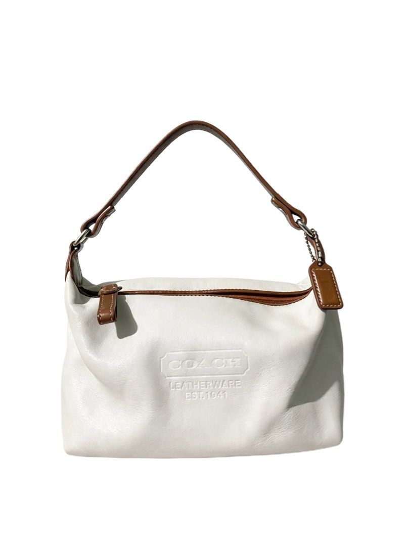 Coach White Leatherware Est 1941 Shoulder Bag (Category: Luxury Bags & Wallets) located in Quezon City. Submitted by un0oo (Listing ID 1465013189, Image 1). Description: - Authentic Coach shoulder bag - Color: White leather with brown contrast strap and trim - Front embossed Coach Leatherware Est 1941 logo - Includes matching brown leather hangtag on a beaded chain - Secure top zipper closure - Compact size, ideal for daily essentials.