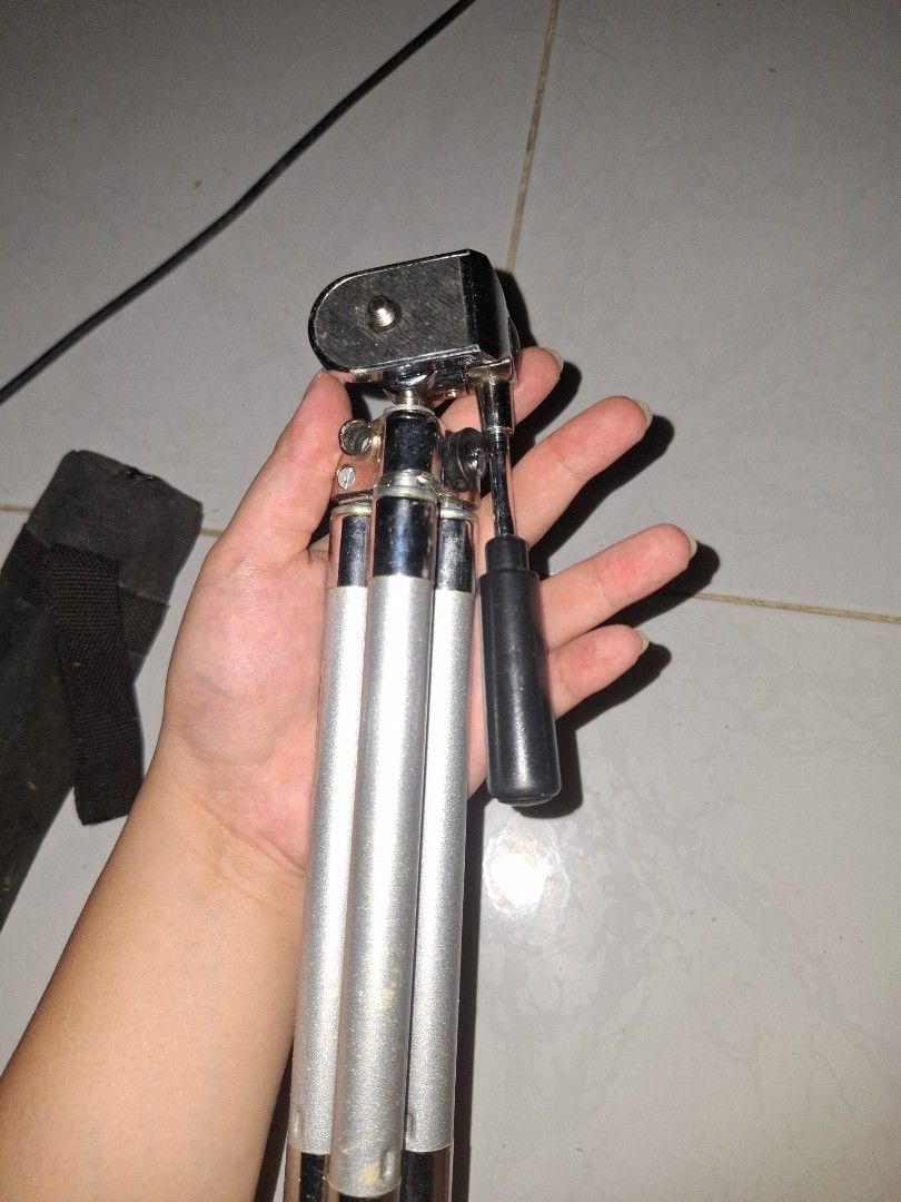 Compact silver metal camera tripod with pan head handle (Category: Tripods & Monopods) located in Manila. Submitted by ogbacsandr04531 (Listing ID 1465100626, Image 2). Description: - Color: Silver and black metal finish - Features: Three extendable legs and adjustable pan head with handle - Compatibility: Standard mounting screw fits most cameras - Portability: Lightweight, collapses compactly, and includes a black fabric carrying case - Best fo