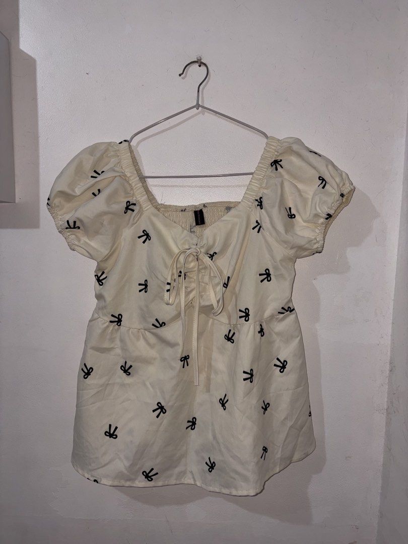Cream Bow Print Puff Sleeve Peplum Blouse (Category: Blouses) located in Manila. Submitted by _8ljay (Listing ID 1465026733, Image 1). Description: - Cream-coloured blouse with black bow pattern - Square neckline & short puff sleeves with elastic cuffs - Adjustable lace-up tie closure at the chest - Flattering peplum style silhouette - Lightweight fabric, perfect for pairing with high-waisted denim or skirts - Fits small to medium frames - Clean 