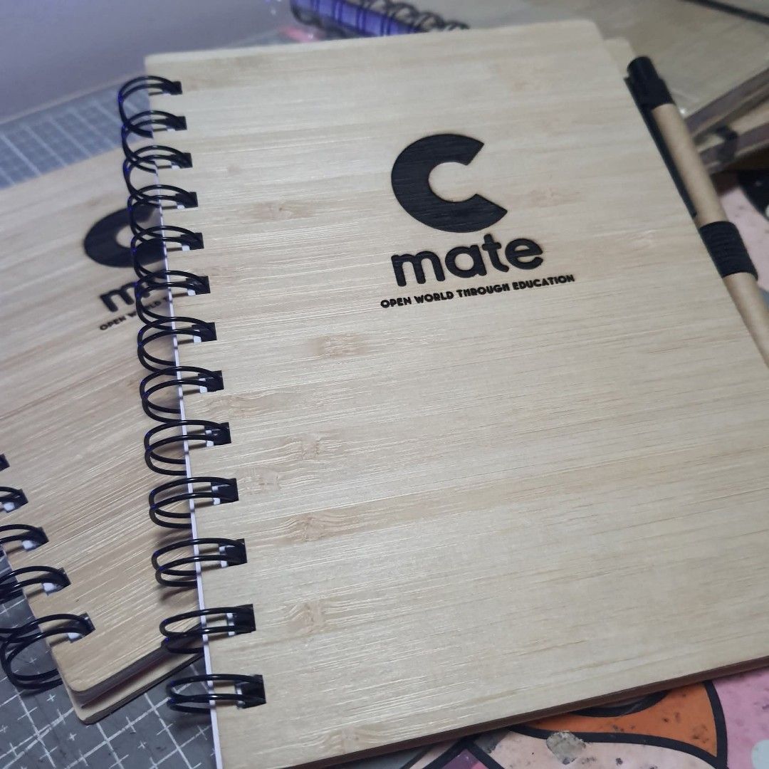 Custom Engraved Bamboo Notebook with Pen (Category: Stationery & School Supplies) located in Tarlac. Submitted by jajubells (Listing ID 1465057041, Image 3). Description: - Material: Eco-friendly bamboo wood cover with spiral binding - Includes: Matching pen secured with an elastic band - Personalization: Free laser-engraved names or custom designs on the cover - Ideal for: Personalized gifts, teachers' day, souvenirs, and corporate giveaways - P