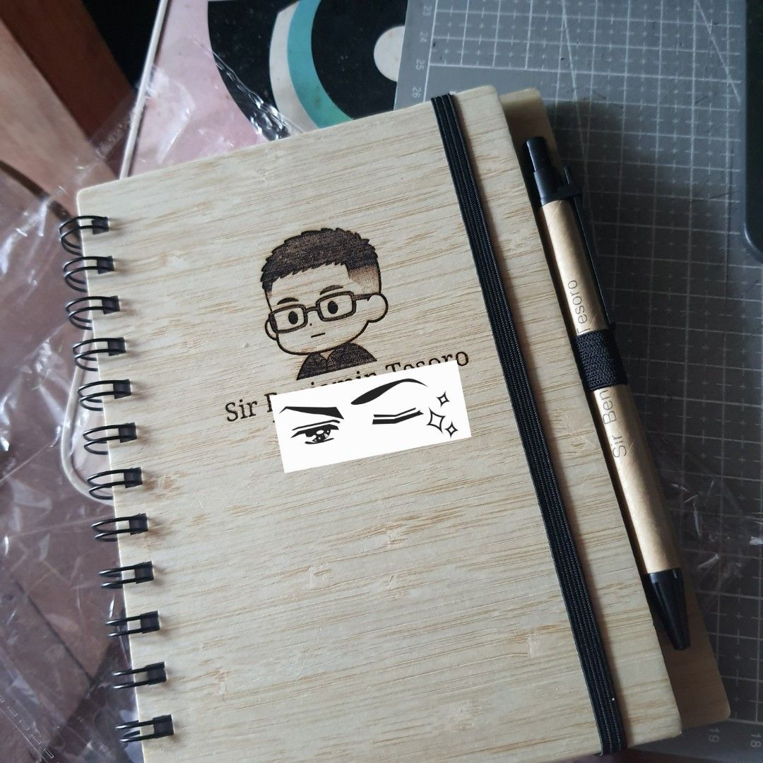 Custom Engraved Bamboo Notebook with Pen (Category: Stationery & School Supplies) located in Tarlac. Submitted by jajubells (Listing ID 1465057041, Image 1). Description: - Material: Eco-friendly bamboo wood cover with spiral binding - Includes: Matching pen secured with an elastic band - Personalization: Free laser-engraved names or custom designs on the cover - Ideal for: Personalized gifts, teachers' day, souvenirs, and corporate giveaways - P