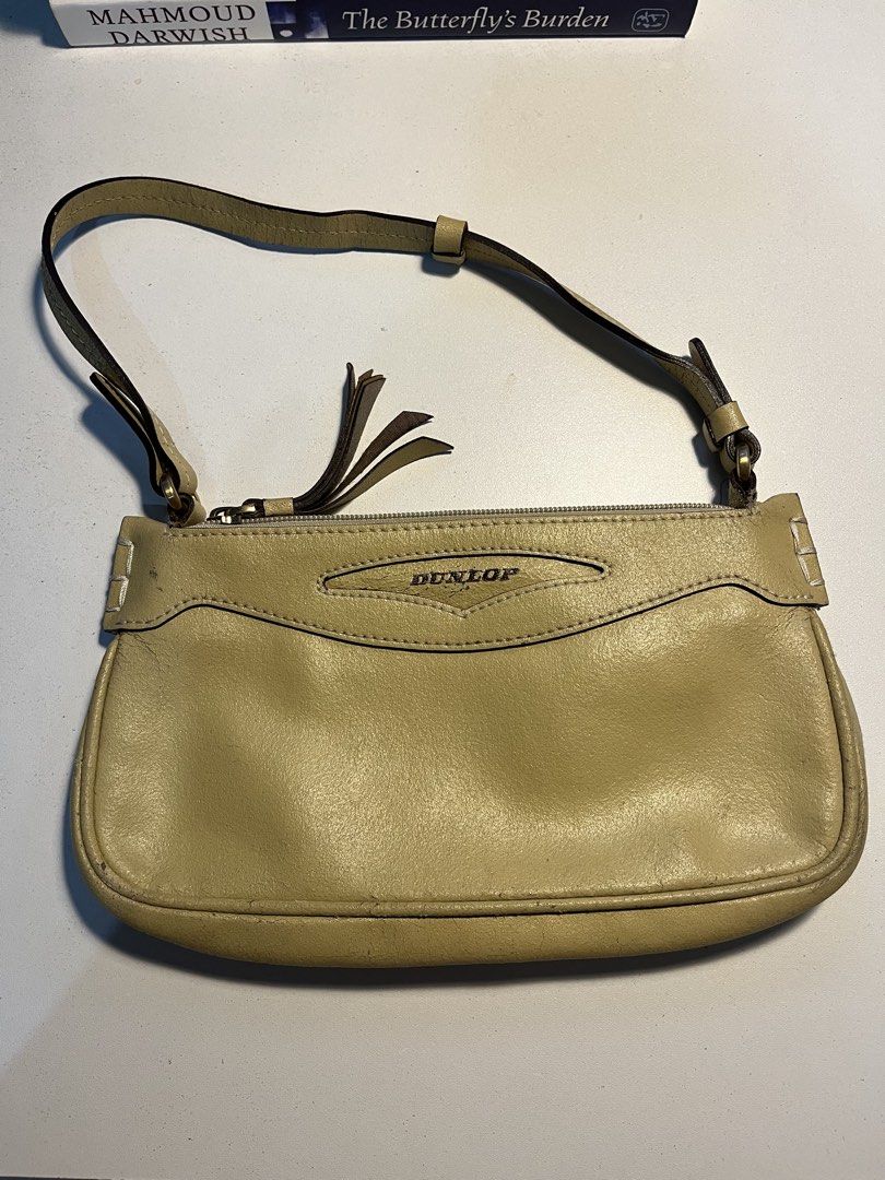 Dunlop Beige Shoulder Bag (Category: Shoulder Bags) located in Quezon City. Submitted by juliacassandr4a (Listing ID 1465118749, Image 1). Description: - Brand/Model: Dunlop beige shoulder bag - Design: Short strap, fringe zipper pull, and top zip closure - Interior: Includes built-in card slots and a zippered pocket - Condition Notes: Noticeable cracking on the strap material, fading on the Dunlop logo, and staining on the inside lining near the