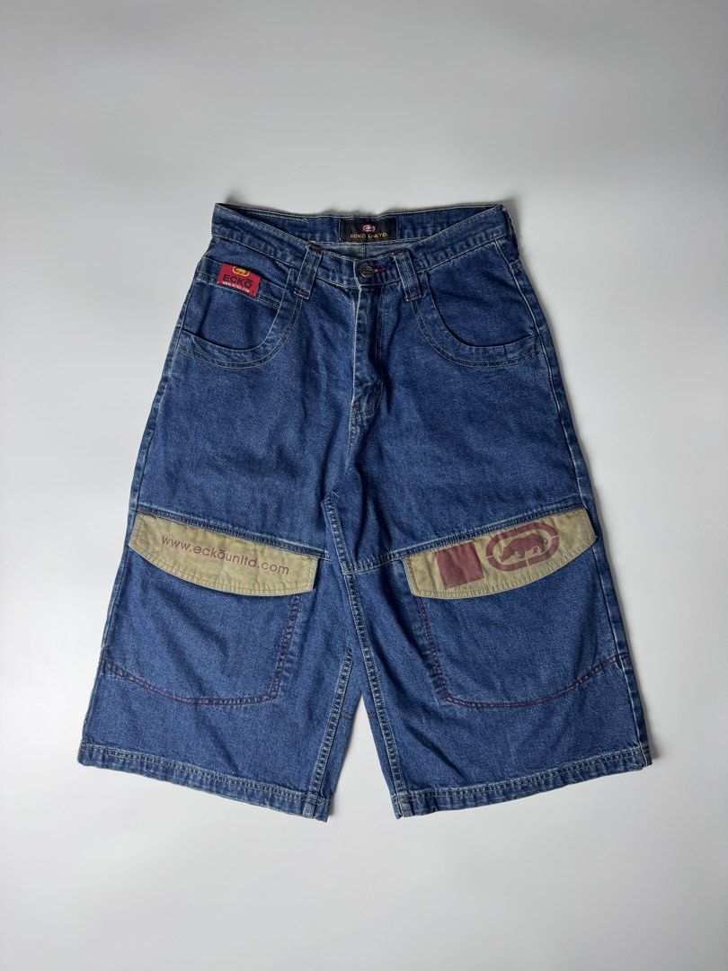Ecko Unltd Denim Shorts Long Jorts (Category: Shorts) located in Cavite. Submitted by dracokidstuff (Listing ID 1465085584, Image 1). Description: - Brand: Ecko Unltd - Style: Vintage Y2K baggy skater denim jorts - Wash: Dark blue with contrast red topstitching - Features: Large front cargo pockets with khaki flaps, rhino logo, web branding, and back leather waistband patch - Size: Flat waist measures roughly 15 inches across.
