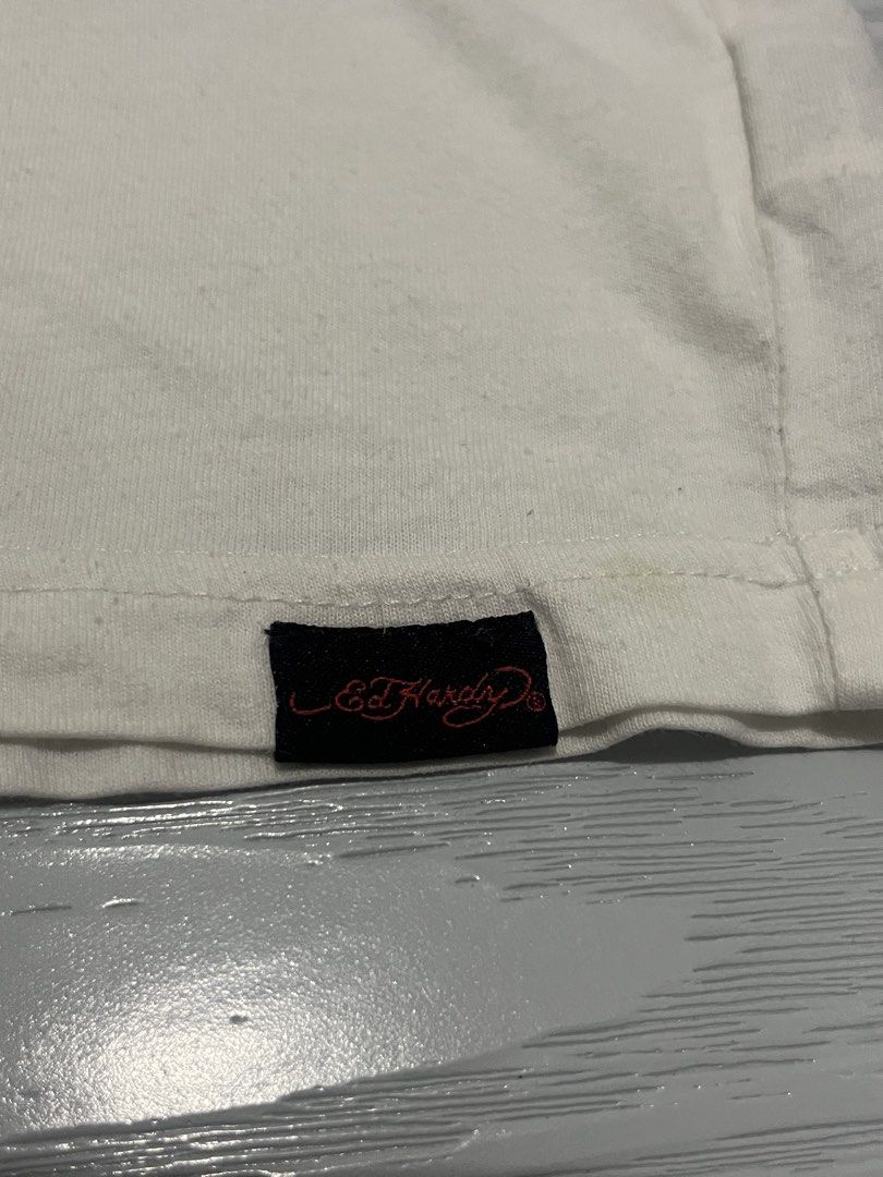 Ed Hardy White Graphic Tee (Complete Tag) (Category: Tshirts & Polo Shirts ) located in Las Pinas. Submitted by 5.1.5kurono (Listing ID 1465149988, Image 3). Description: Available ✅ Ed Hardy Tee ₱200 • width: 22 • length: 27 Issue: • pinhole near tag • needs wash since na stock lang 📍 las piñas, ph • j&t / lalamove 📦 • sf shouldered by buyer • gcash only 💸 (payment first) color may vary due to lighting all items are thrifted please manage you