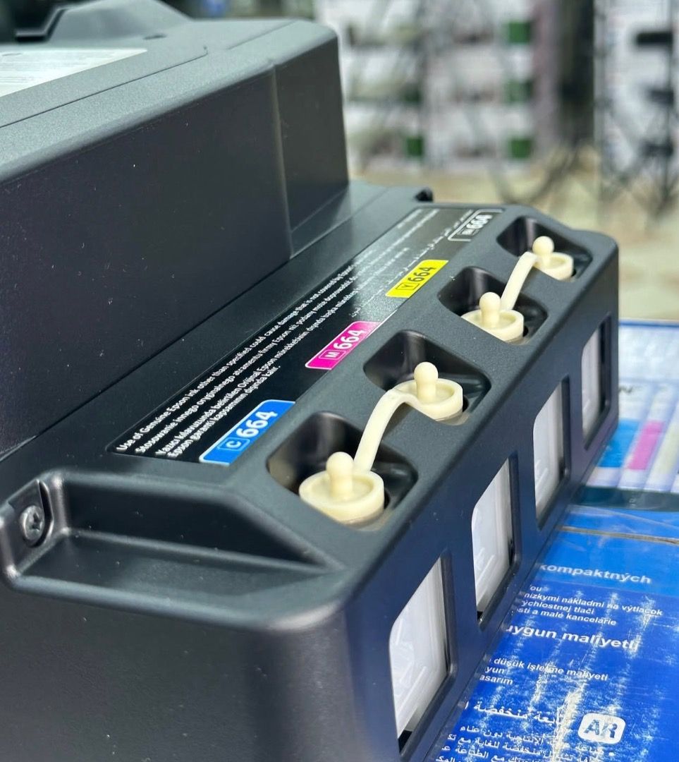 Epson EcoTank L121 Printer with Ink Bottles (Category: Printers, Scanners & Copiers) located in Lubao. Submitted by silentturtle_5f8fa7 (Listing ID 1465148244, Image 3). Description: - Brand: Epson EcoTank L121 - Color: Black - Condition: Brand new, unused, with original blue protective tape intact - Inclusion: Original box - Ink: Complete set of four 664 ink bottles (Black, Cyan, Magenta, Yellow) - Features: Built-in ink tank system visible on t
