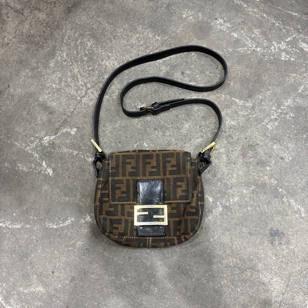 Fendi Mini Zucca FF Baguette (Category: Luxury Bags & Wallets) located in Zamboanga. Submitted by thriftyyali (Listing ID 1465100795, Image 1). Description: - Authentic Fendi Zucca canvas pattern in classic brown and black - Sleek black leather strap and front magnetic flap closure - Elegant gold-tone hardware with engraved FENDI lettering - Stamped 'Made in Italy' tag near the front lock mechanism - Perfect luxury everyday or statement bag.