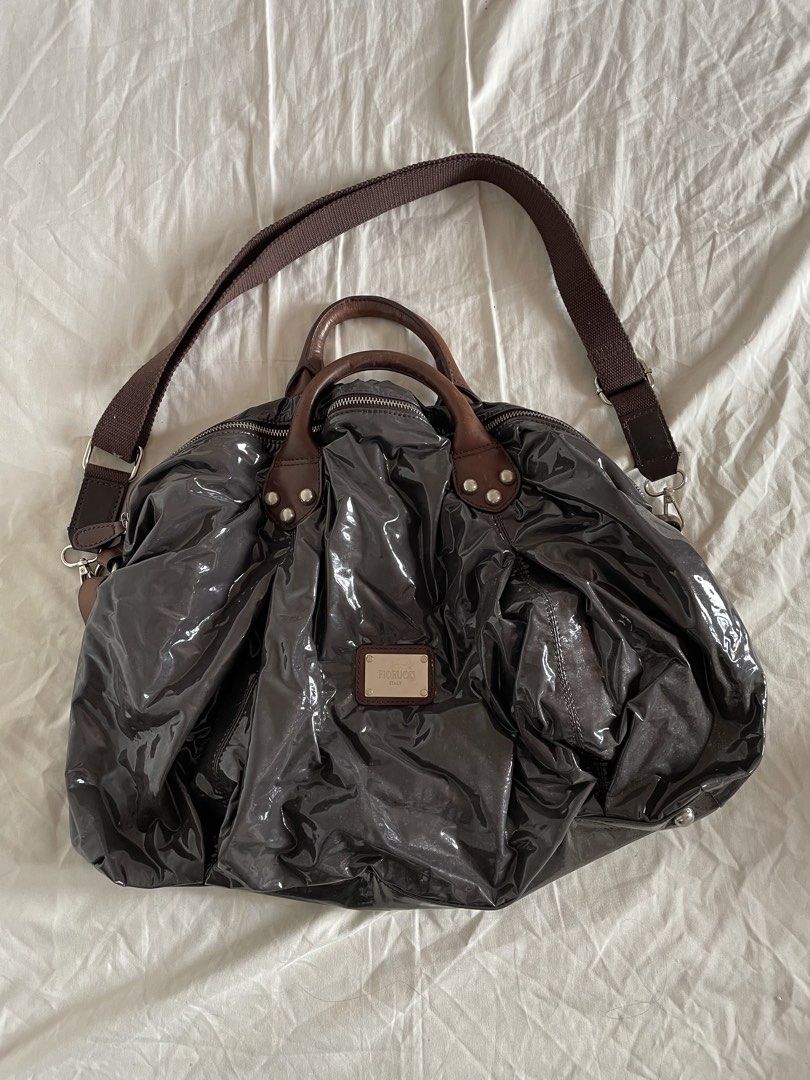 Fiorucci Large Dumpling Sling Bag (Category: Shoulder Bags) located in Bacoor. Submitted by j0skopo (Listing ID 1465038830, Image 1). Description: - Brand: Fiorucci - Size: Large - Color: Dark purple with a glossy patent finish - Straps: Dual top carry genuine leather handles, and an adjustable fabric crossbody strap - Hardware: Silver-tone with engraved brand details and protective metal base feet - Interior: Spacious fabric-lined compartment wi