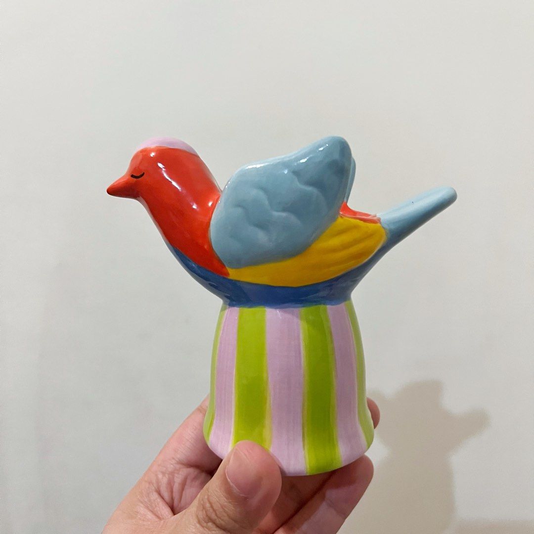 Flying Tiger Copenhagen Ceramic Bird Figurine Holder (Category: Vases & Decorative Bowls) located in San Pedro. Submitted by rainyydayy (Listing ID 1464856921, Image 1). Description: - Brand: Flying Tiger Copenhagen - Material: Glossy ceramic - Design: Multicolor bird with red head, blue wings, and striped pink-and-green base - Function: Decorative piece or small trinket tray with open top - Authenticity: Bottom stamped with Zebra A/S branding an