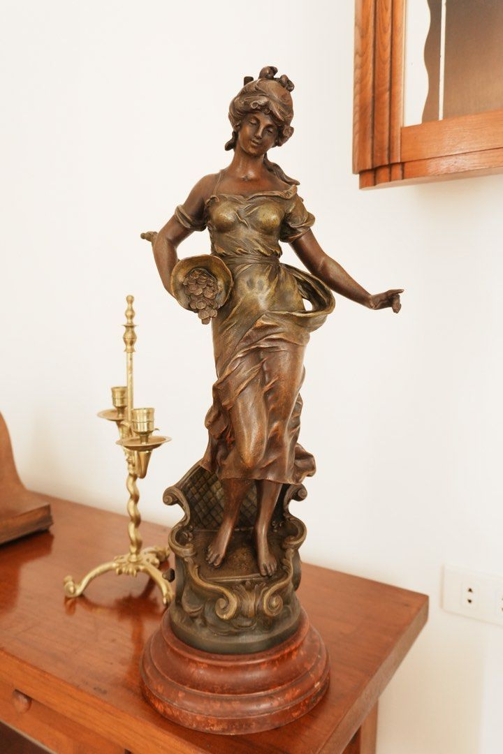 Fortune & Abundance - Decorative Female Figure (Category: Vintage Collectibles) located in Manila. Submitted by heleensym (Listing ID 1464970010, Image 2). Description: A graceful allegorical figure holding a horn of plenty overflowing with coins, symbolising prosperity and good fortune. Flowing drapery and warm bronze-coloured and gold-toned finishes complement an ornate scrollwork pedestal and stepped circular base. An expressive decorative acc