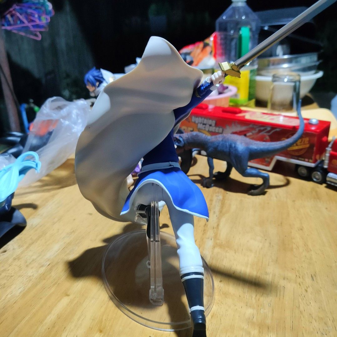 Frieren Himmel Action Figure Dynamic Pose with Sword (Category: Figurines & Statues) located in Plaridel. Submitted by klayskolektibols (Listing ID 1465090901, Image 3). Description: - Character: Himmel from Frieren - Material: Dynamic PVC figure - Details: Blue hair, blue mage outfit, flowing white cape, and blue-bladed sword mid-action - Stand: Clear round base with support stems for secure display - Condition: Clean piece with great paint deta