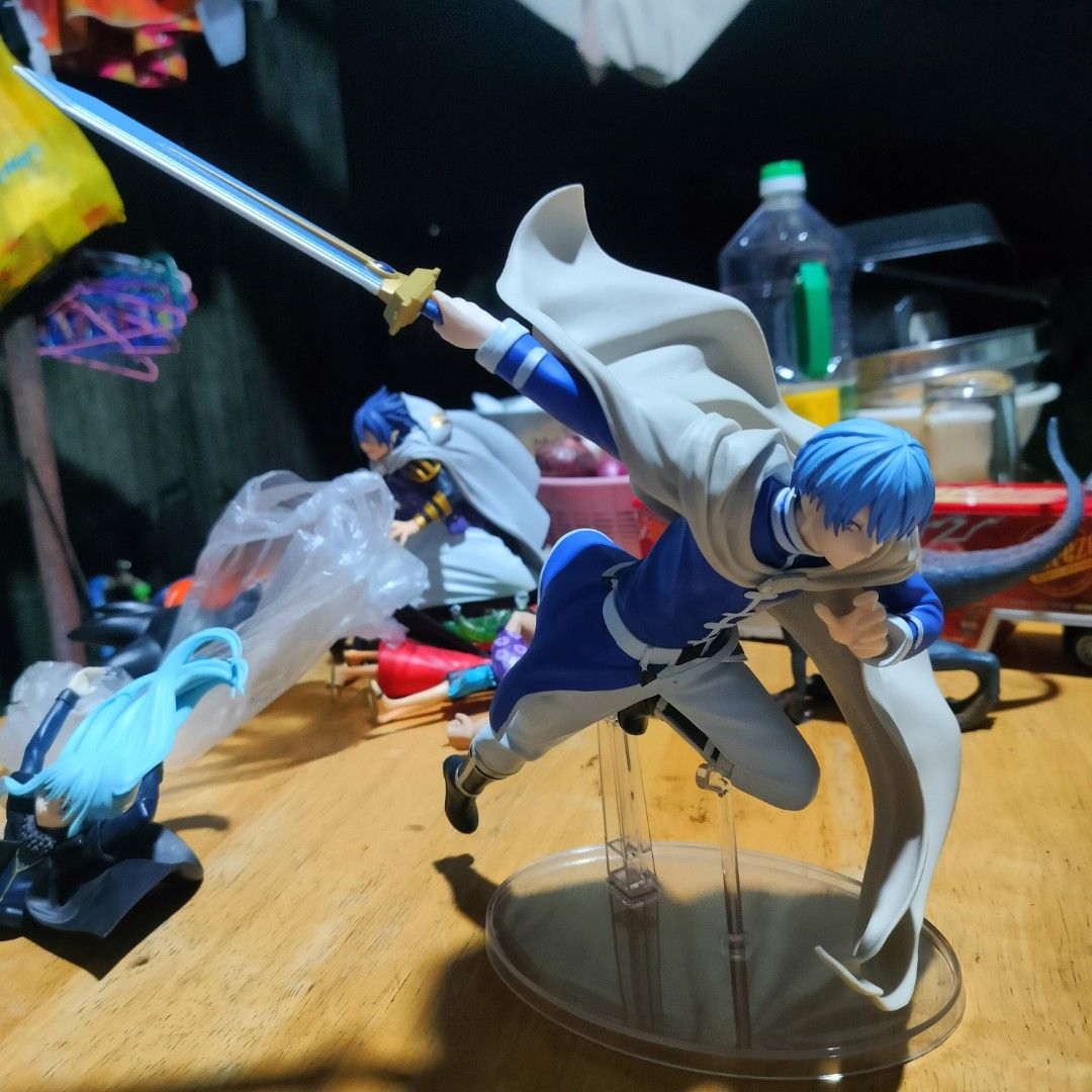 Frieren Himmel Action Figure Dynamic Pose with Sword (Category: Figurines & Statues) located in Plaridel. Submitted by klayskolektibols (Listing ID 1465090901, Image 1). Description: - Character: Himmel from Frieren - Material: Dynamic PVC figure - Details: Blue hair, blue mage outfit, flowing white cape, and blue-bladed sword mid-action - Stand: Clear round base with support stems for secure display - Condition: Clean piece with great paint deta