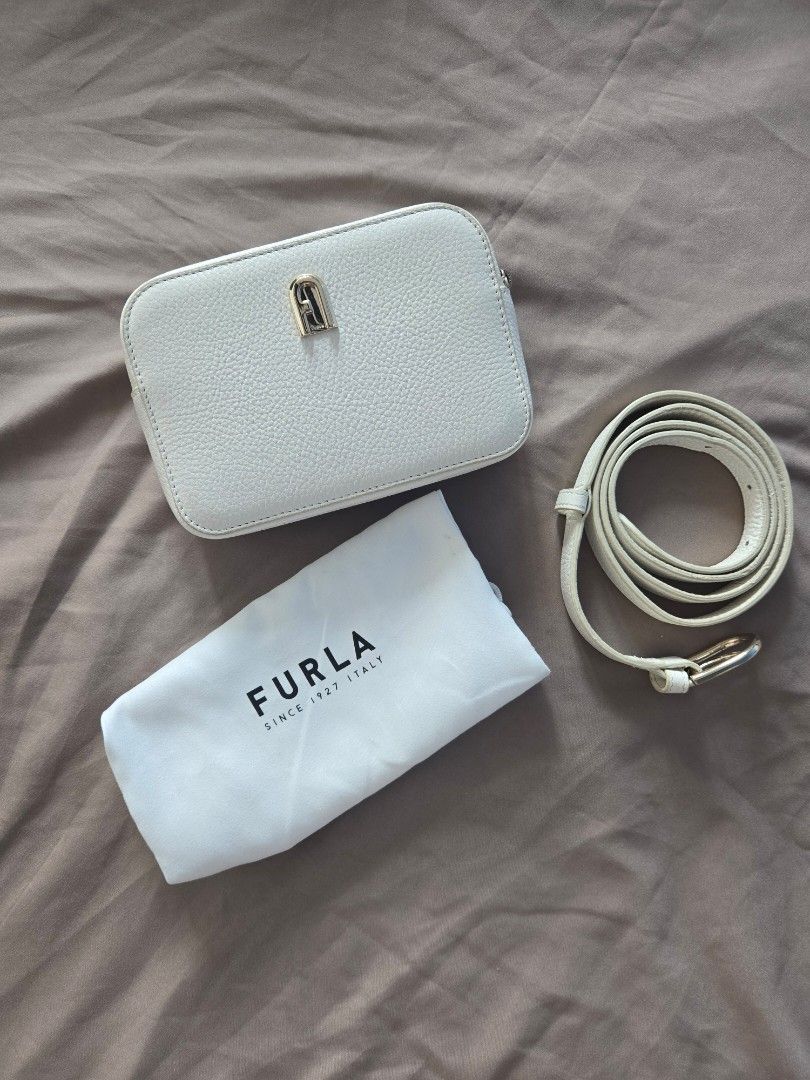 Furla White Leather Crossbody Bag (Category: Cross-body Bags) located in Marikina City. Submitted by aj.preloved (Listing ID 1465001530, Image 1). Description: - Brand: Furla - Material: White pebbled leather - Hardware: Gold-tone - Style: Compact rectangular bag with zip closure - can wear as crossbody or as a belt bag - Inclusion: Original white dust bag and strap DM for more photos.