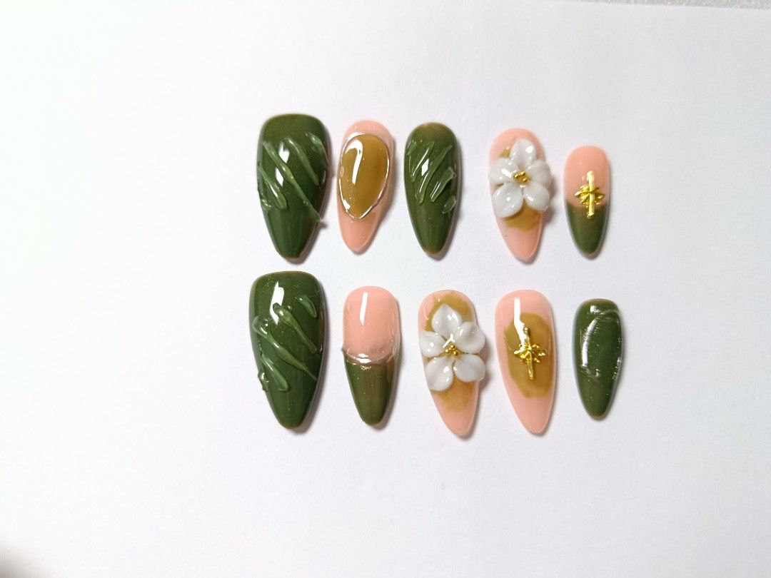 Green Floral Press-On Nails Set (Category: Hands & Nails) located in Manila. Submitted by thebossbabe (Listing ID 1465104314, Image 1). Description: - Design: Olive green and nude with 3D white floral details, gold star charms, glossy textured patterns, and abstract gel art - Shape: Elegant almond - Quantity: Full set of 10 handmade false nails - Usage: Reusable, apply with nail glue or adhesive tabs - Occasion: Versatile for chic everyday wear o