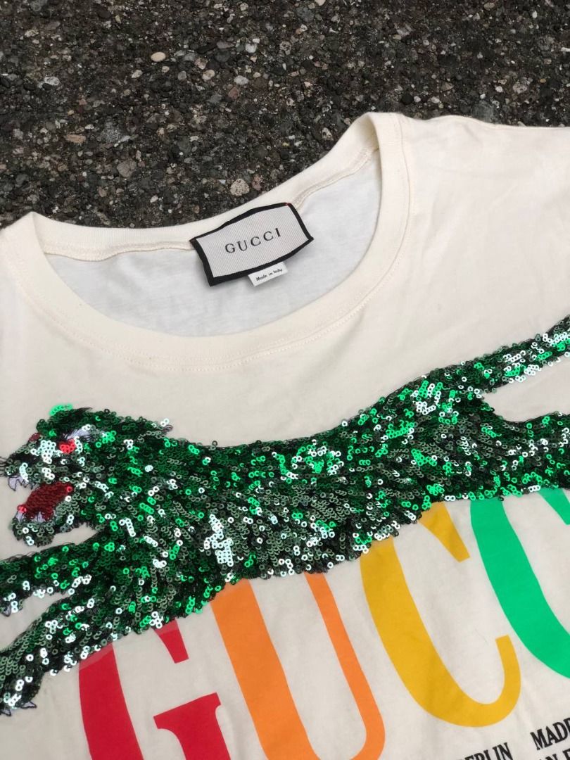 Gucci Sequin Tiger Multicolor Cities Logo T-Shirt (Category: Luxury Apparel) located in Tacloban City. Submitted by thedropout (Listing ID 1465050935, Image 2). Description: - Authentic Gucci graphic tee in off-white cotton - Features vibrant multicolor rainbow lettering with city names - Stunning green sequin tiger patch meticulously stitched on the front - Premium heavyweight fabric with a pristine, clean collar - Includes classic Gucci interio