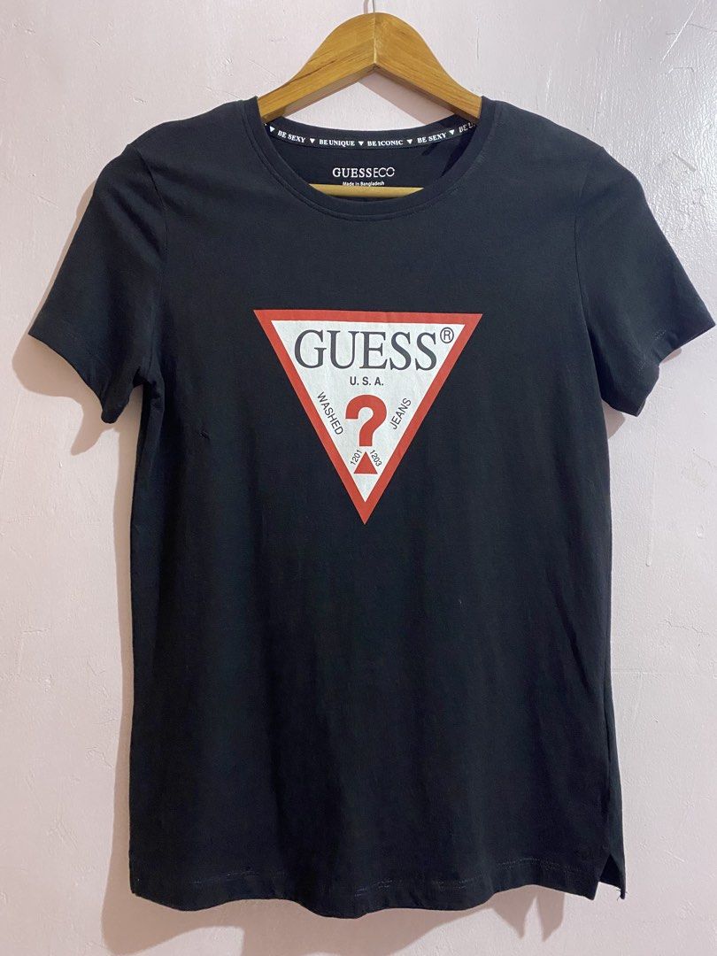 Guess Black Triangle Logo Tee (Category: Shirts) located in Cavite. Submitted by luxxe.muse (Listing ID 1465097670, Image 1). Description: - Brand: Guess - Color: Black - Design: Classic red and white triangle logo on front - Fit & Style: Standard fit, crew neck, short sleeves - Material: Comfortable cotton - Flaw: Noticeable small hole on the left side near the logo - Condition: Pre-loved, perfect for casual everyday wear -Bust 36 - Has a small 