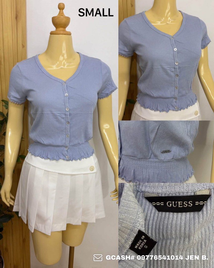 Guess Blue Ribbed Button-Down Short Sleeve Top (Category: Blouses) located in Tagum. Submitted by bernardino49694 (Listing ID 1465008202, Image 1). Description: - Brand: Guess - Size: S - Color: Pastel blue - Material: Soft, stretchy fabric (Made in Korea) - Design: Short sleeves, V-neck, front button closure with metal buttons - Details: Smocked ruffled hem with small metal Guess logo tag.