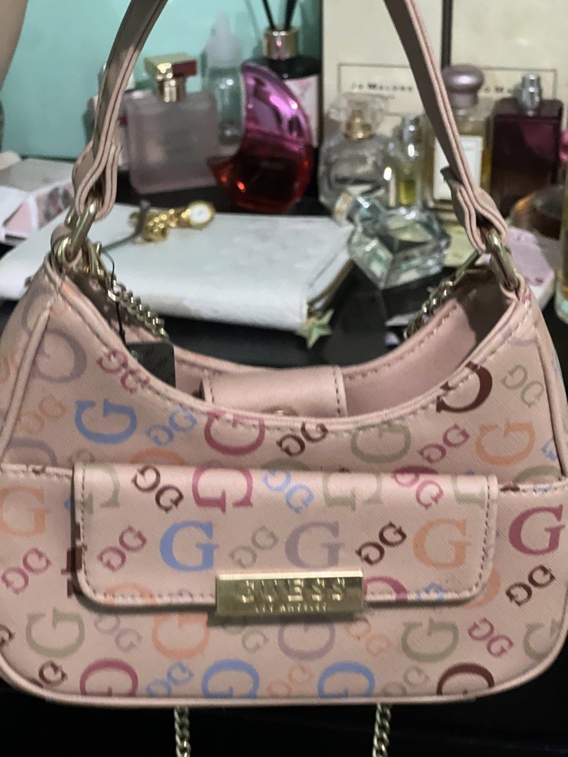 Guess Pink Multicolor Logo Shoulder Bag (Category: Shoulder Bags) located in Manila. Submitted by cleverstone_21f597 (Listing ID 1465098695, Image 2). Description: Guess shoulder bag in pink with multicolored logo print all over. Front flap pocket featuring gold-tone hardware and logo plaque. Top handle design with an additional chain strap attached. Structured mini shape, compact size for daily essentials..