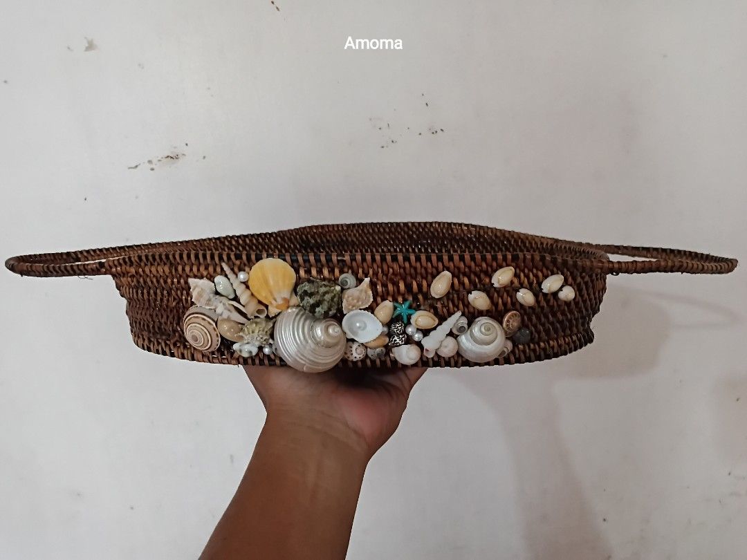 Handmade woven nito basket decorated with seashells (Category: Dinnerware & Cutlery) located in Taguig. Submitted by amomaenterprise (Listing ID 1464971801, Image 1). Description: - Material: Dark brown woven rattan with real seashell decorations - Design: Dual side handles, deep sides, and a flat oval base - Style: Natural coastal, hand-crafted look - Use: Ideal for organizing small items on coffee tables or vanities - size: 12.5in x 8in .