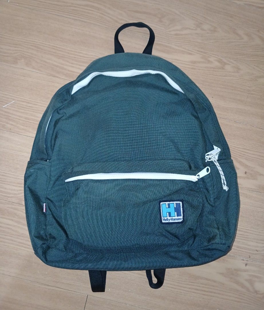 Helly Hansen Green Backpack Daypack (Category: Backpacks) located in Daraga. Submitted by thethriftcity2024 (Listing ID 1465169517, Image 1). Description: - Brand: Helly Hansen - Color: Dark green with white zippers and dark blue lining - Features: Front zip pocket, adjustable padded straps, top grab handle - Details: Classic retro embroidered logo patch on front - Condition: Clean interior, all zippers fully functional - Origin: Made in Vietnam 