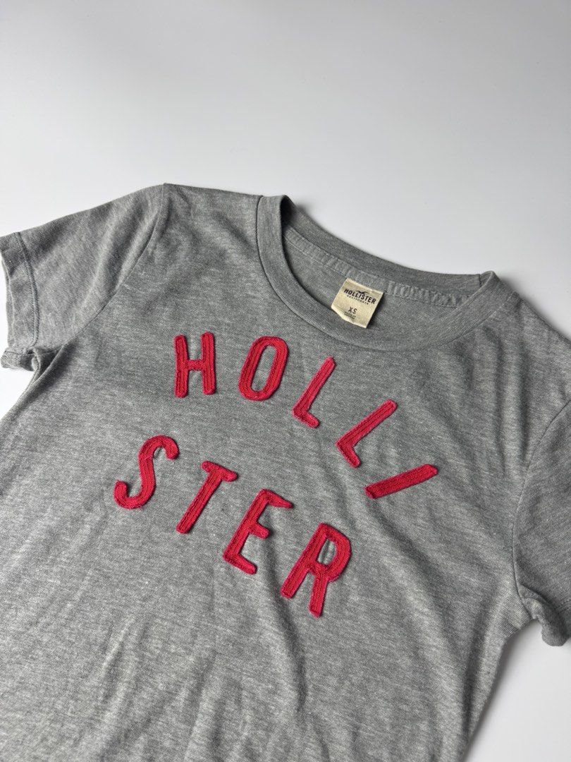 Hollister Grey Graphic Tee Size XS (Category: Shirts) located in Manila. Submitted by babygirly2k (Listing ID 1465080462, Image 2). Description: - Brand: Hollister - Size: Extra Small (XS) - Color: Grey with red embroidered chest lettering - Fit: Classic crew neck, short sleeves - Material: Comfortable cotton blend - Origin: Made in Vietnam - Condition: Clean, excellent everyday basic.
